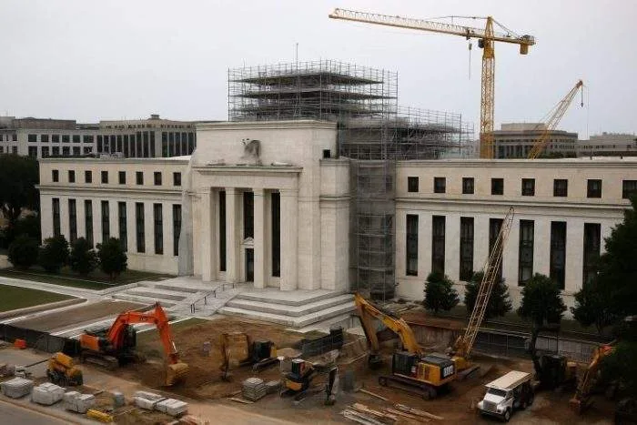 Aerial view of the Marriner S. Eccles Federal Reserve building under renovation, with scaffolding, cranes, and heavy machinery present on site.