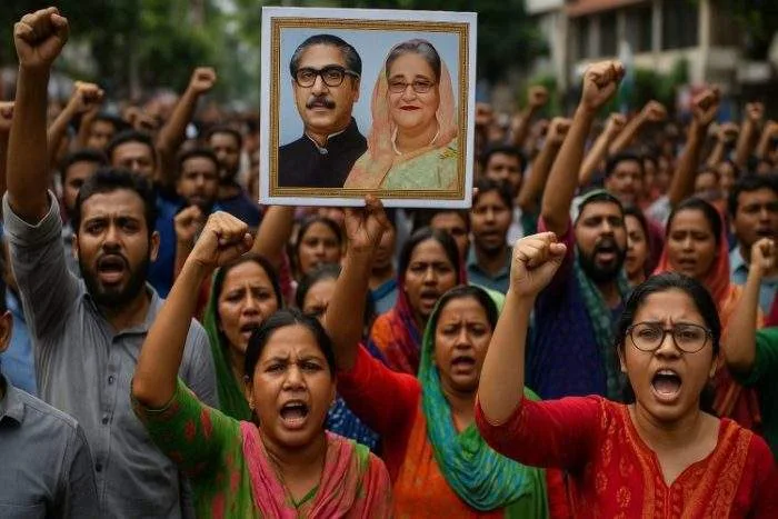 A protest scene in Bangladesh where demonstrators hold up a placard featuring Bangabandhu Sheikh Mujibur Rahman and Sheikh Hasina.