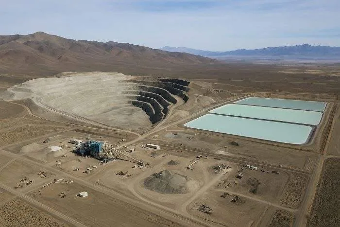 Aerial view of the Thacker Pass lithium mining site in Nevada, showing a vast open-pit mine, evaporation ponds, and industrial facilities surrounded by desert mountains.