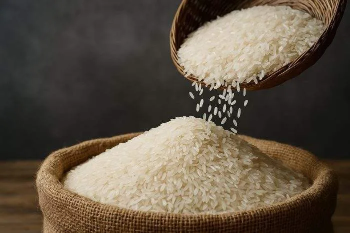 Close-up of white rice pouring from a wicker basket into a burlap sack.
