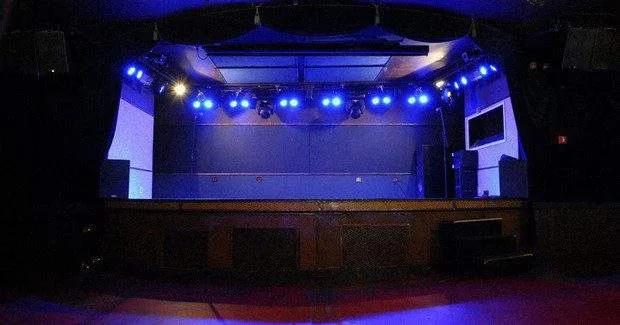 An empty concert arena with dim stage lighting, symbolizing the sudden cancellation of Japanese music events in Shanghai.