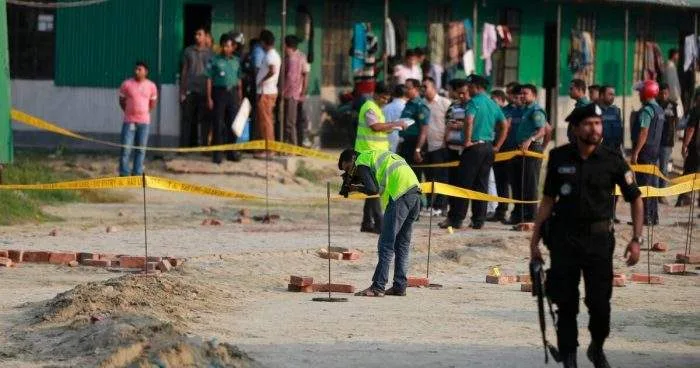 Damaged madrasa building in South Keraniganj after an explosion, with debris visible and police securing the area.