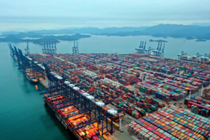 Cargo containers and automobile exports at a Mexican port symbolizing new trade tariffs on Indian goods.