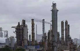 A large oil tanker, green and grey, docked at the Pascagoula, Mississippi, oil terminal, discharging crude oil via heavy-duty hoses into the refinery’s pipeline network.