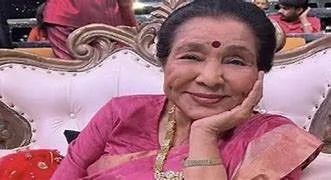 A vintage microphone and gramophone in front of a blurred portrait of Asha Bhosle, representing her legendary musical legacy.