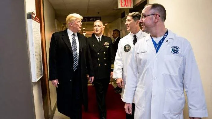 A formal medical brief stamped with the White House insignia resting on a dark wooden desk next to a stethoscope.