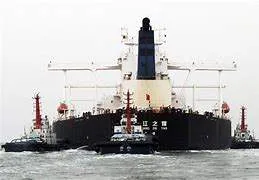 A high-angle shot of a massive oil tanker (VLCC) navigating through the narrow Lombok Strait, with Indonesian tropical islands in the background.