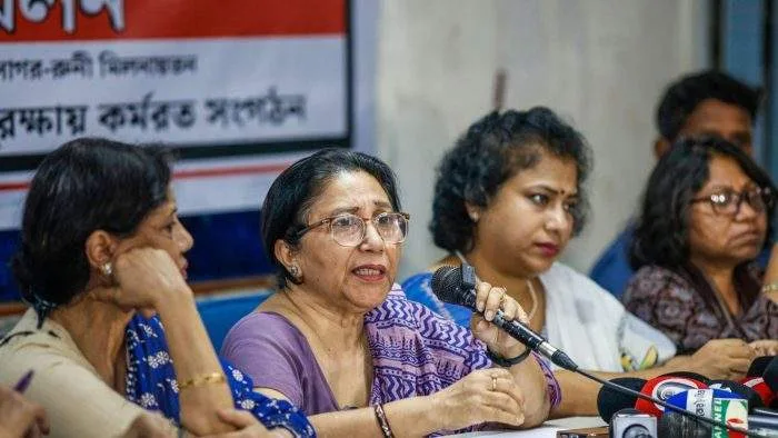 A crowded press briefing table at the Dhaka Reporters Unity, with prominent female rights activists including Shaheen Anam addressing a bank of microphones.