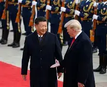 President Donald Trump and President Xi Jinping shaking hands in front of the Great Hall of the People in Beijing, surrounded by US and Chinese flags.