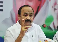 V. D. Satheesan waving to a crowd of supporters in Kerala, with Congress and UDF flags visible in the background.