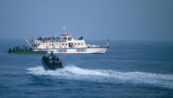 A fleet of activist vessels sailing in international waters under European and humanitarian flags, intercepted by naval patrol boats.