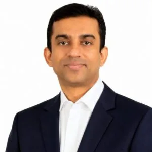 A professional file photograph of Mahbub Hasan Ripon speaking in a formal setting. He is dressed in a dark vest over a light-colored long-sleeve shirt, maintaining a serious and focused expression. The background is softly blurred to keep full visual attention on the speaker, capturing an official political address atmosphere.