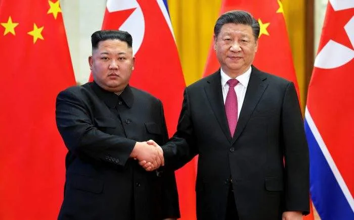 Chinese President Xi Jinping and North Korean leader Kim Jong Un standing together on a red carpet during an official welcoming ceremony in Pyongyang.