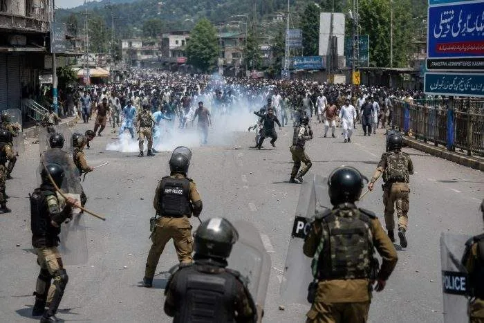 Horizontal view of smoke rising from a street blocked with burning tires and stones in Muzaffarabad.