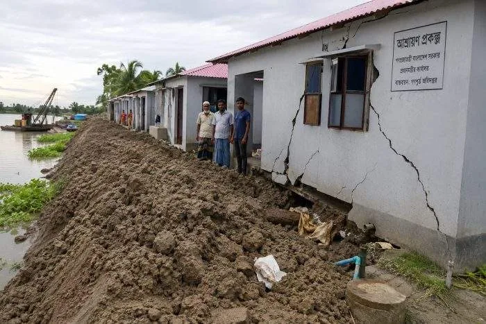 Horizontal view of damaged government-built Ashrayan houses with cracked walls due to piled river soil in Dumuria.