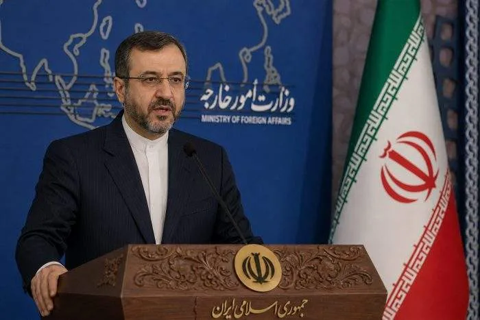 Horizontal shot of the Iranian Foreign Ministry building in Tehran with state media broadcasting equipment outside.