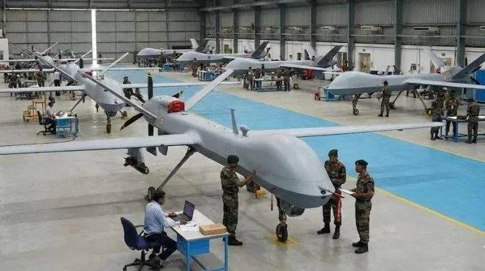 A sleek, dark grey military-grade surveillance drone resting on an open runway asphalt under a dramatic cloud-filled sky.