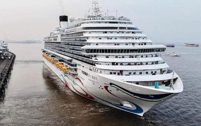 Wide horizontal shot of the massive Adora Magic City cruise ship sailing on the open sea.