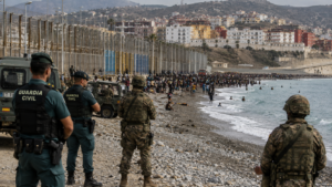 Horizontal shot showing Spanish Civil Guard officers and military personnel monitoring Tarajal beach in Ceuta.